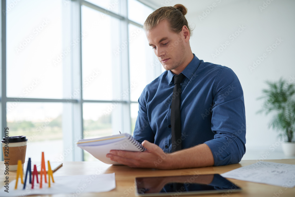 Portrait of young businessman checking information in his planner Portrait of young businessman checking information in his planner