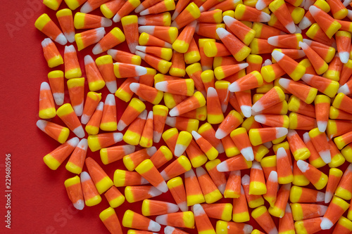 Big pile of Halloween candy corn on an orange background 