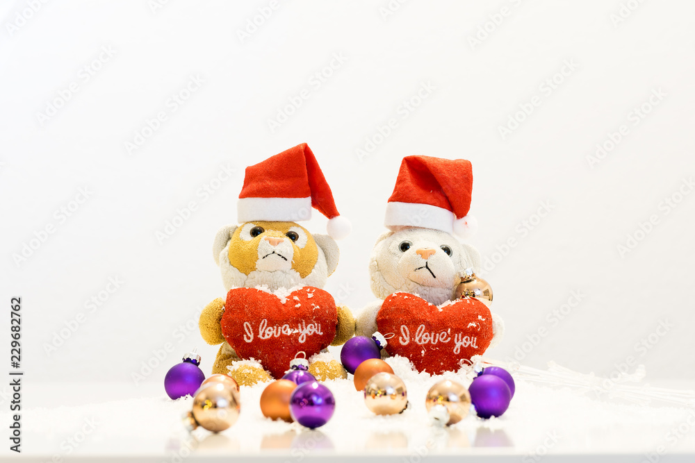 Zwei Teddybören mit Weihnachtsmützen sitzen auf Schnee mit Christbaumkugeln im Vordergrund