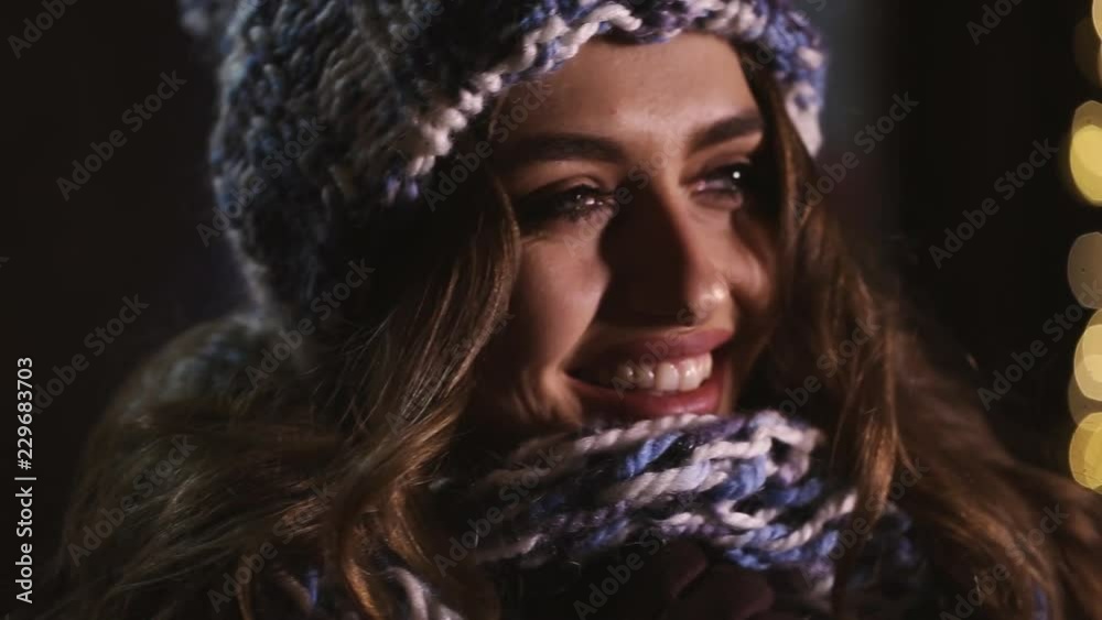 Beautiful smiling brunette in a winter hat in the night city. Beautiful smiling brunette in a winter hat in the night city.
