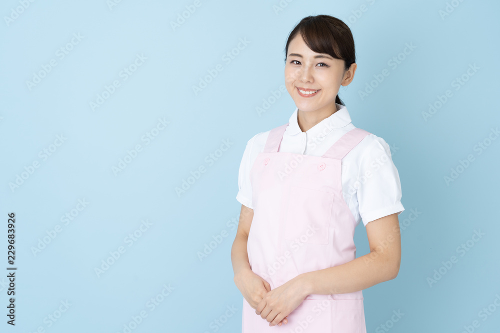 portrait of young asian nurse wearing apron on blue background portrait of young asian nurse wearing apron on blue background