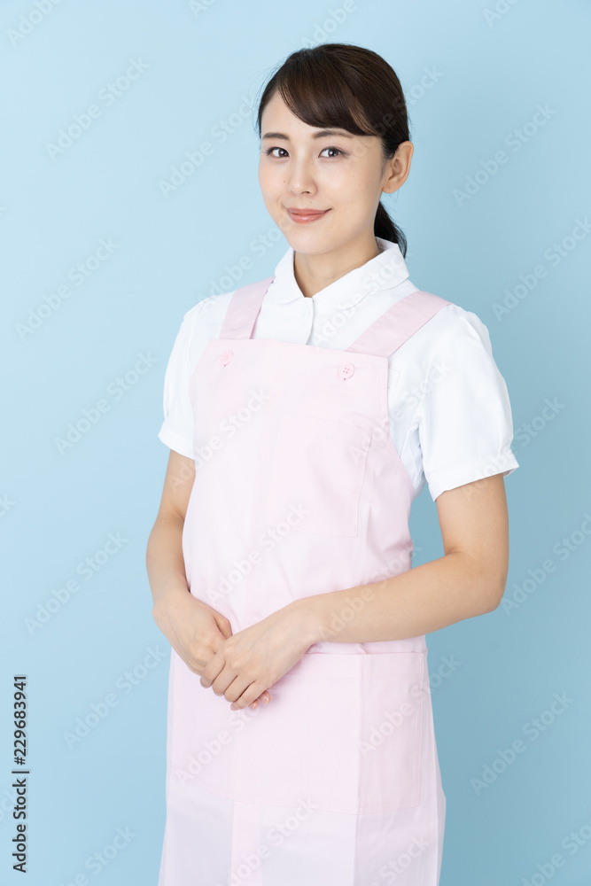 portrait of young asian nurse wearing apron on blue background portrait of young asian nurse wearing apron on blue background