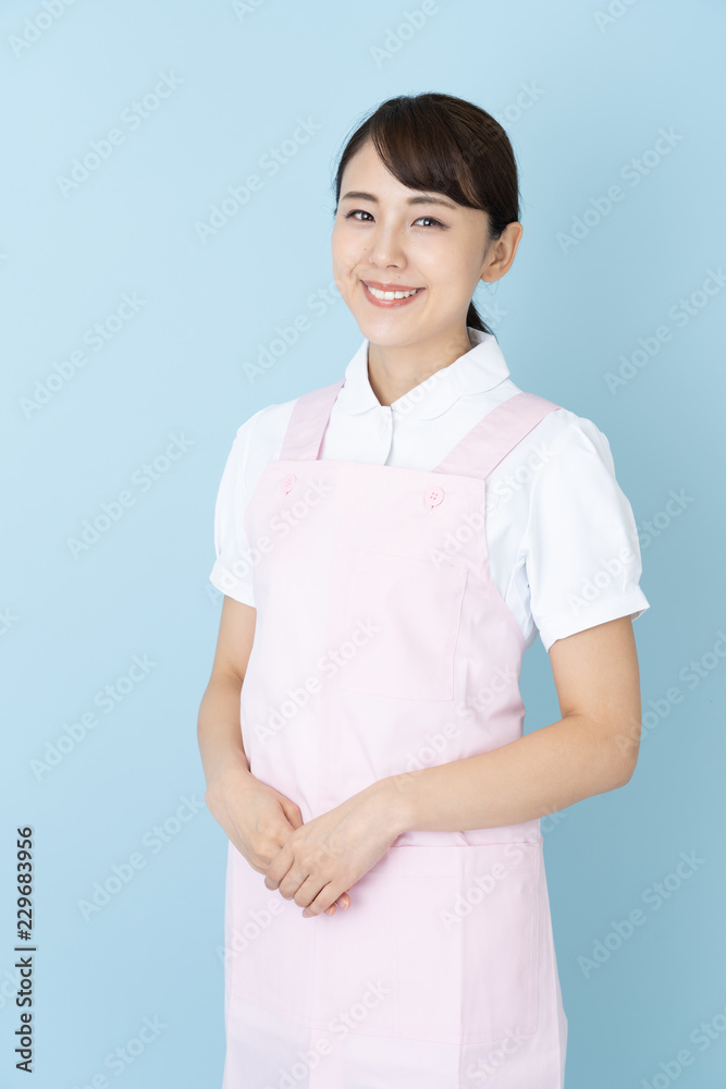 portrait of young asian nurse wearing apron on blue background portrait of young asian nurse wearing apron on blue background