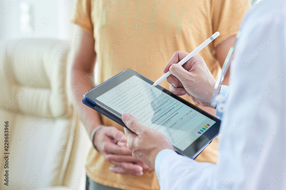 Doctor filling medical card on digital tablet when talking to patient - obrazy, fototapety, plakaty 