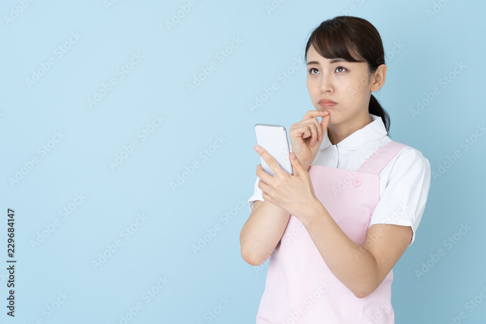 portrait of young asian nurse wearing apron on blue background