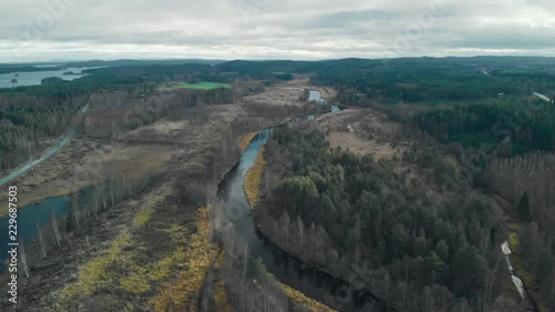 Aerial, drone shot, flying over a river surrounded by leafless autumn forest, on a cloudy fall day, in Juuka, Pohjois-Karjala, Finland photo