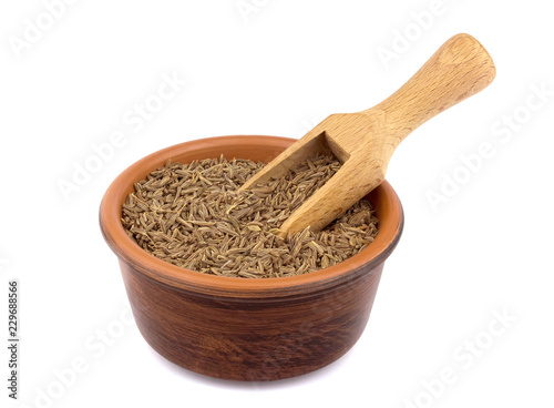 Cumin seed in the bowl isolated on white background with a wooden scoop