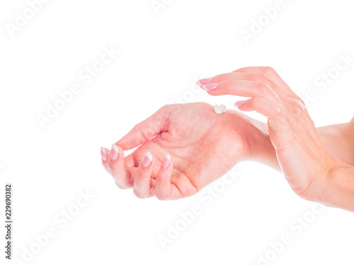 Closeup of beautiful female hands applying hand cream isolated on white background.