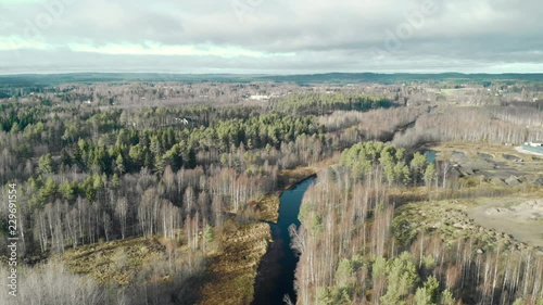 Aerial, drone shot, flying towards a river, in a leafless, autumn forest, on a cold, half cloudy, fall day, in Juuka, North Karelia, Finland photo