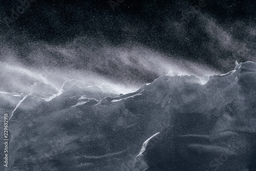 Wind blows fresh snow over an embankment