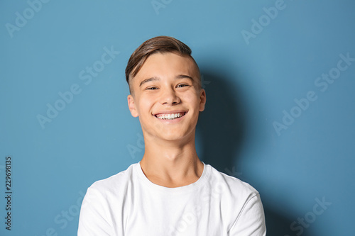 Smiling teenage boy on color background photo