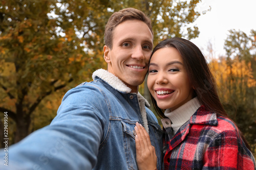 Happy loving couple taking selfie in autumn park