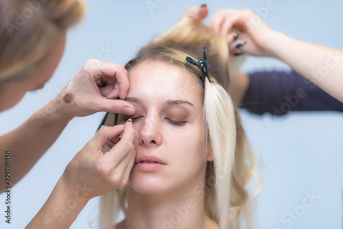 The work of a professional make-up artist  beautician  makes makeup on the face of a blonde girl with shadows on the eyes.