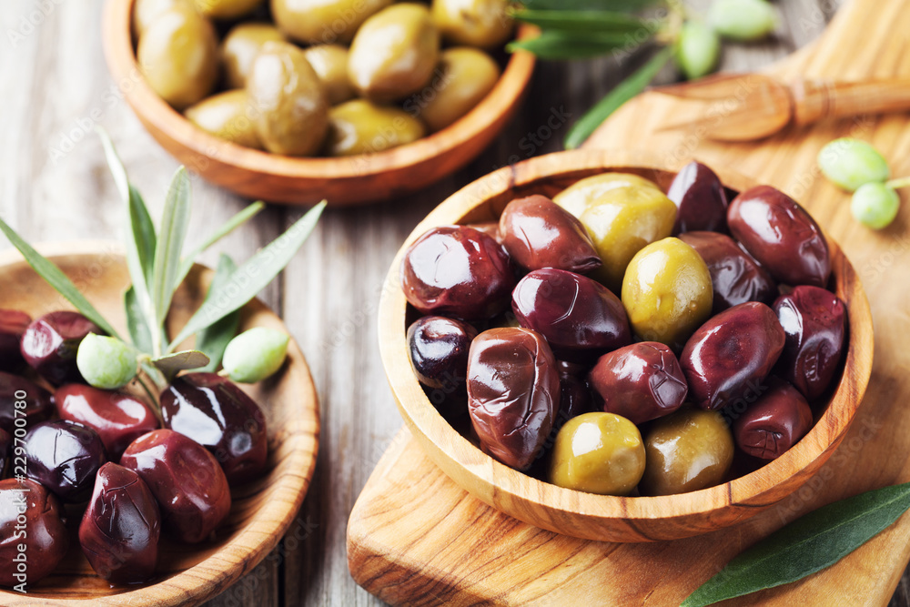 Set from olives in wooden bowls decorated with fresh olive tree branch. Set from olives in wooden bowls decorated with fresh olive tree branch.