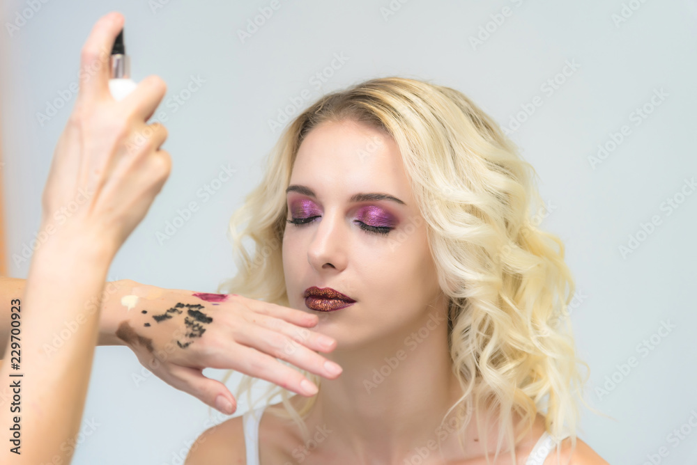 The work of a professional makeup artist - beautician, makes up a brush on the face on the lips of a beautiful blonde. The work of a professional makeup artist - beautician, makes up a brush on the face on the lips of a beautiful blonde.