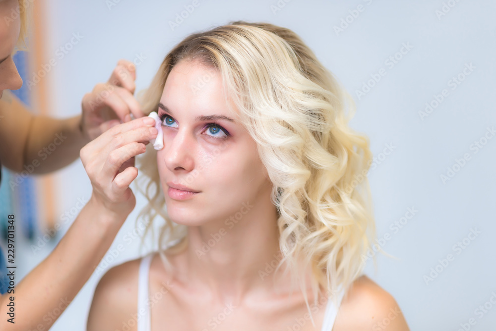 The work of a professional make-up artist, beautician, makes makeup on the face of a blonde girl with shadows on the eyes. The work of a professional make-up artist, beautician, makes makeup on the face of a blonde girl with shadows on the eyes.