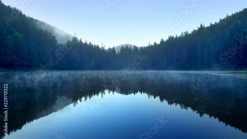 Wallpaper Mural Clear blue mountain lake covered with low fog Aerial flight from water surface level Reflections of sky and mountains falling in water Torontodigital.ca