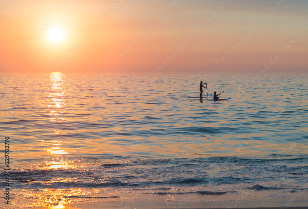 Blick auf das Meer, bei Sonnenuntergang mit Stand Up Paddlern, am Strand von Camps Bay, bei Kapstadt in Südafrika