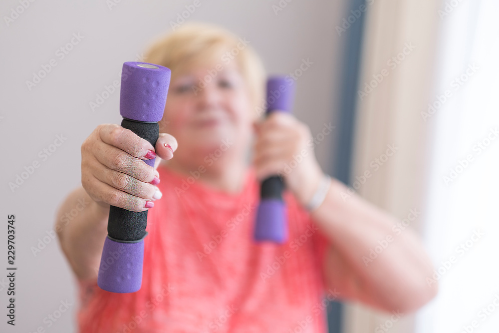 Senior woman training, doing fitness with pink weights at home. Senior woman training, doing fitness with pink weights at home.