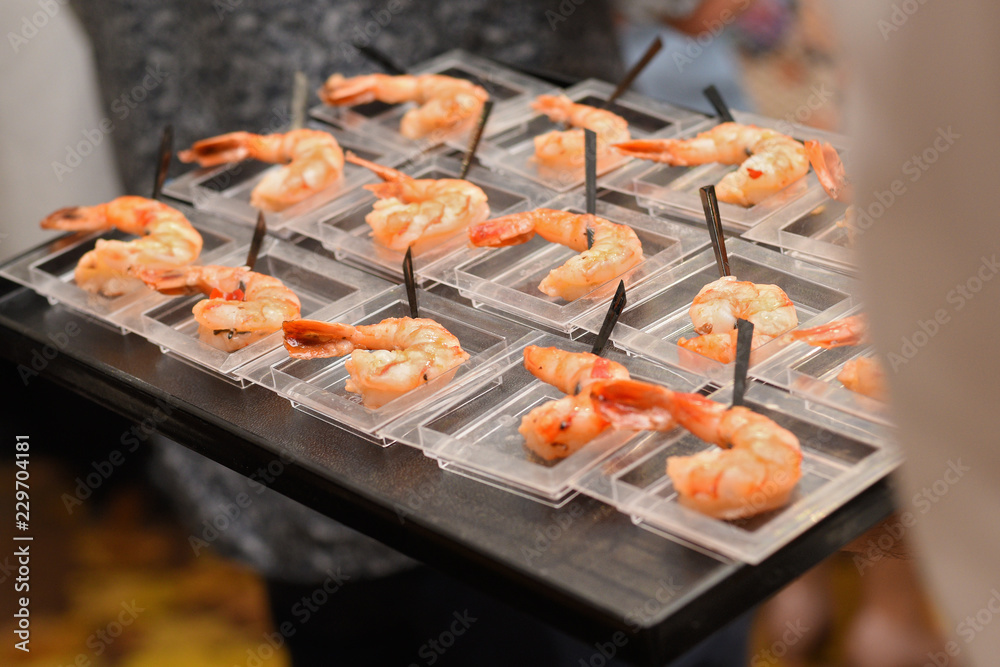 waiter with a tray serving fried shrimp appetizers during a festive dinner waiter with a tray serving fried shrimp appetizers during a festive dinner