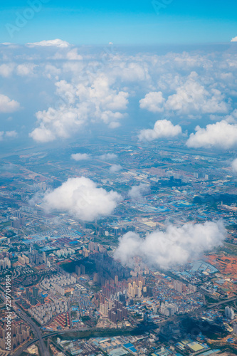 aerial view, flying above the puffy white clouds and over ground landscape in China, Asia.