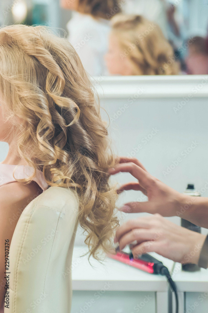 Naklejka premium Hairdressing services. Сreating hairstyle. Hair styling process. Children's hairdressing salon.