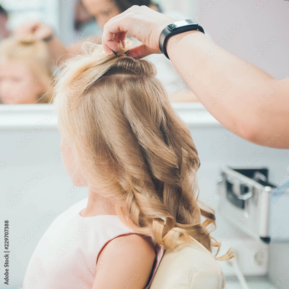 Fototapeta premium Hairdressing services. Сreating hairstyle. Hair styling process. Children's hairdressing salon.