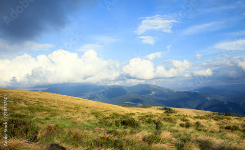 big white clouds in the mountains on the peak, yellow grass, scenery view