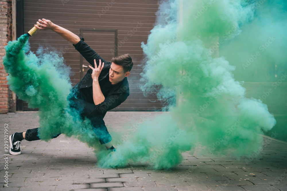 handsome young male dancer in green smoke on street