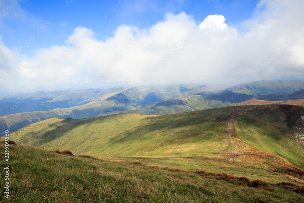 green mountain ridge, grey clouds blue hills on the background