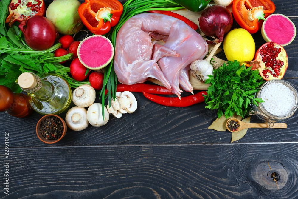 rabbit raw meat, vegetables, fruits, mushrooms spices on a dark rustic