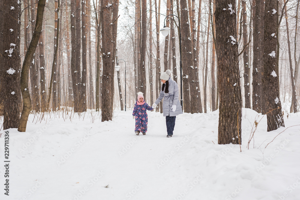 Motherhood, children and nature concept - Attractive young woman and adorable child walking in park