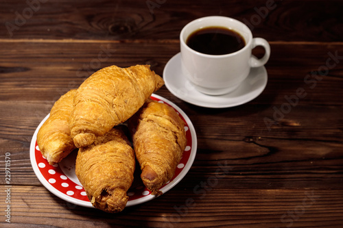 Fototapeta Naklejka Na Ścianę i Meble -  Cup of coffee and plate with fresh croissants on wooden table