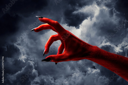 Billede på lærred Halloween red devil monster hand with black fingernails against a dark sky