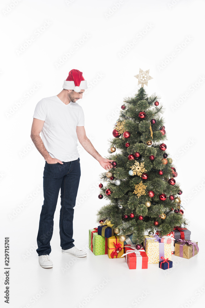 man in santa claus hat standing near christmas tree isolated on white man in santa claus hat standing near christmas tree isolated on white