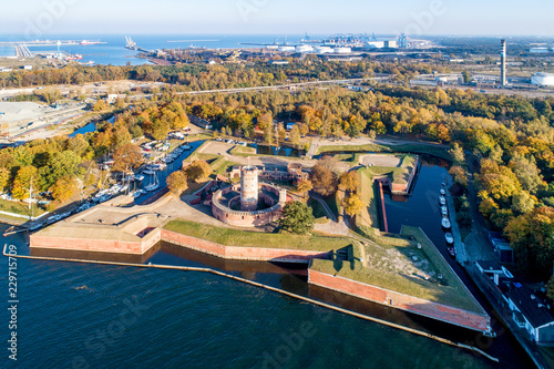 Medieval Wisloujscie Fortress with old lighthouse tower in port of Gdansk, Poland. A unique monument of the fortification works. Aerial view at sunset. Exterior Northern  Gdansk port in the background