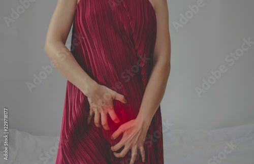 The woman has itching on his genitals.Asian women wear red clothes on their bed, they have itching in the vagina.Girl hands placed at the vagina.Do not focus on objects.