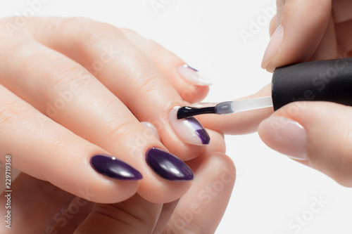 Beautiful well-groomed womans hands. Process of applying decorative nail