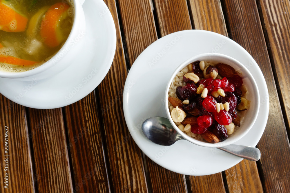 healthy breakfast: oatmeal with dried fruits, nuts and honey and a cup of hot citrus tea healthy breakfast: oatmeal with dried fruits, nuts and honey and a cup of hot citrus tea