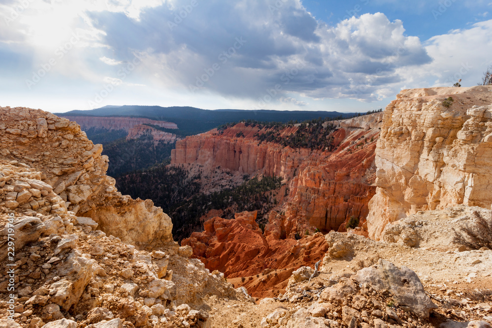 Bryce Canyon National Park high view point vast forest and mountains landscape. The red sandstone rock formations on the foreground and clouds in the sky