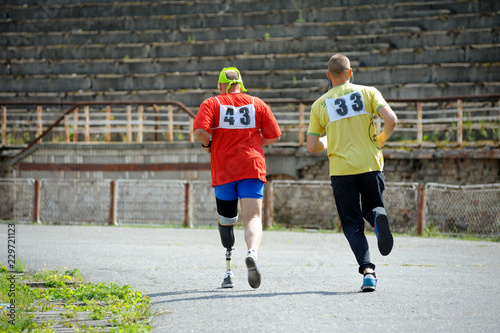 Disabled athlete (left) with an artificial leg running on a track