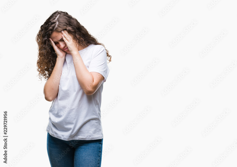 Beautiful brunette curly hair young girl wearing casual t-shirt over isolated background with sad expression covering face with hands while crying. Depression concept.