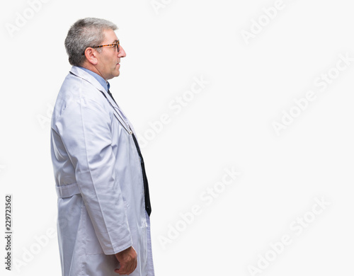 Handsome senior doctor man over isolated background looking to side, relax profile pose with natural face with confident smile. © Krakenimages.com