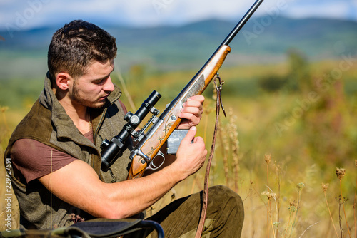 Hunting equipment concept. Hunter khaki clothes ready to hunt nature background. Hunting shooting trophy. Hunter with rifle looking for animal. Hunting hobby and leisure. Man charging hunting rifle