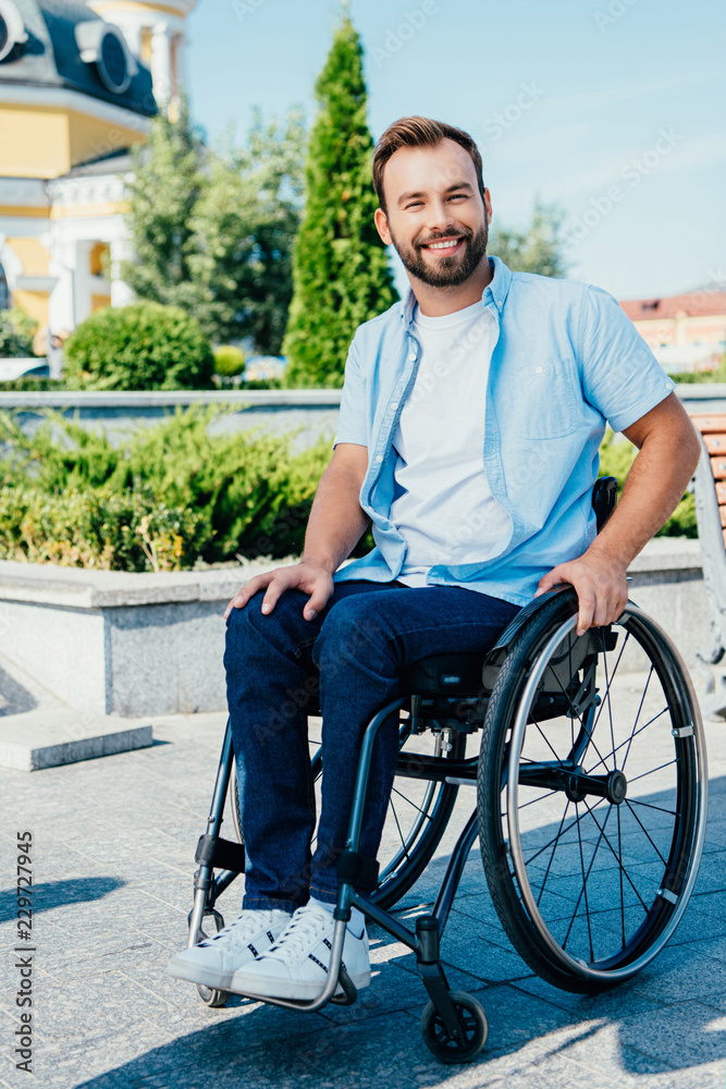 smiling handsome man in wheelchair looking at camera on street smiling handsome man in wheelchair looking at camera on street