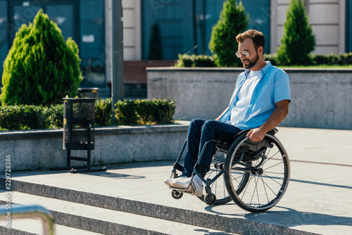 handsome man in sunglasses using wheelchair on street looking at stairs without ramp © LIGHTFIELD STUDIOS