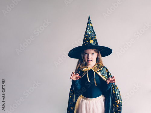 cute girl in a witch costume on a halloween on a light background