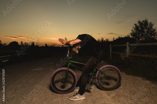 Young man standing bmx bike. BMX rider with and a sunset