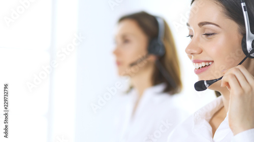 Group of call center operators at work. Focus on beautiful business woman in headset