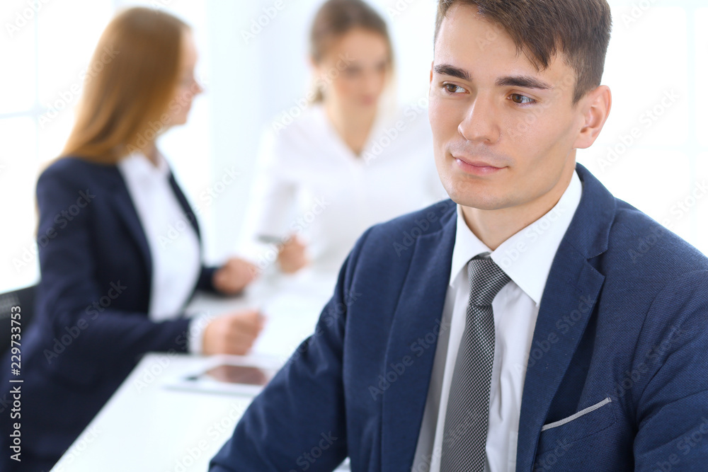 Group of business people or lawyers discussing terms of transaction in office. Focus at young businessman. Meeting and teamwork concept Group of business people or lawyers discussing terms of transaction in office. Focus at young businessman. Meeting and teamwork concept